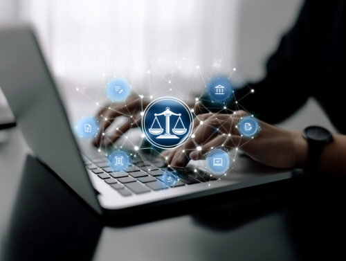 Person tippt auf einem Laptop mit eingeblendeten Symbolen – Darstellung von Legal-Tech-Konzept.
